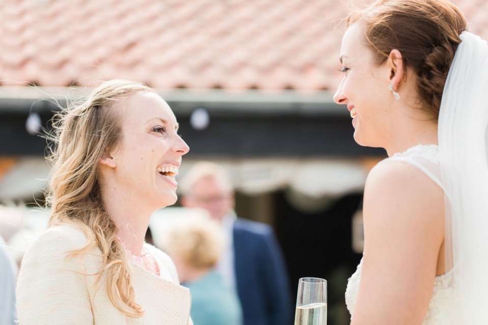 twee vrouwen lachen en praten op een bruiloft