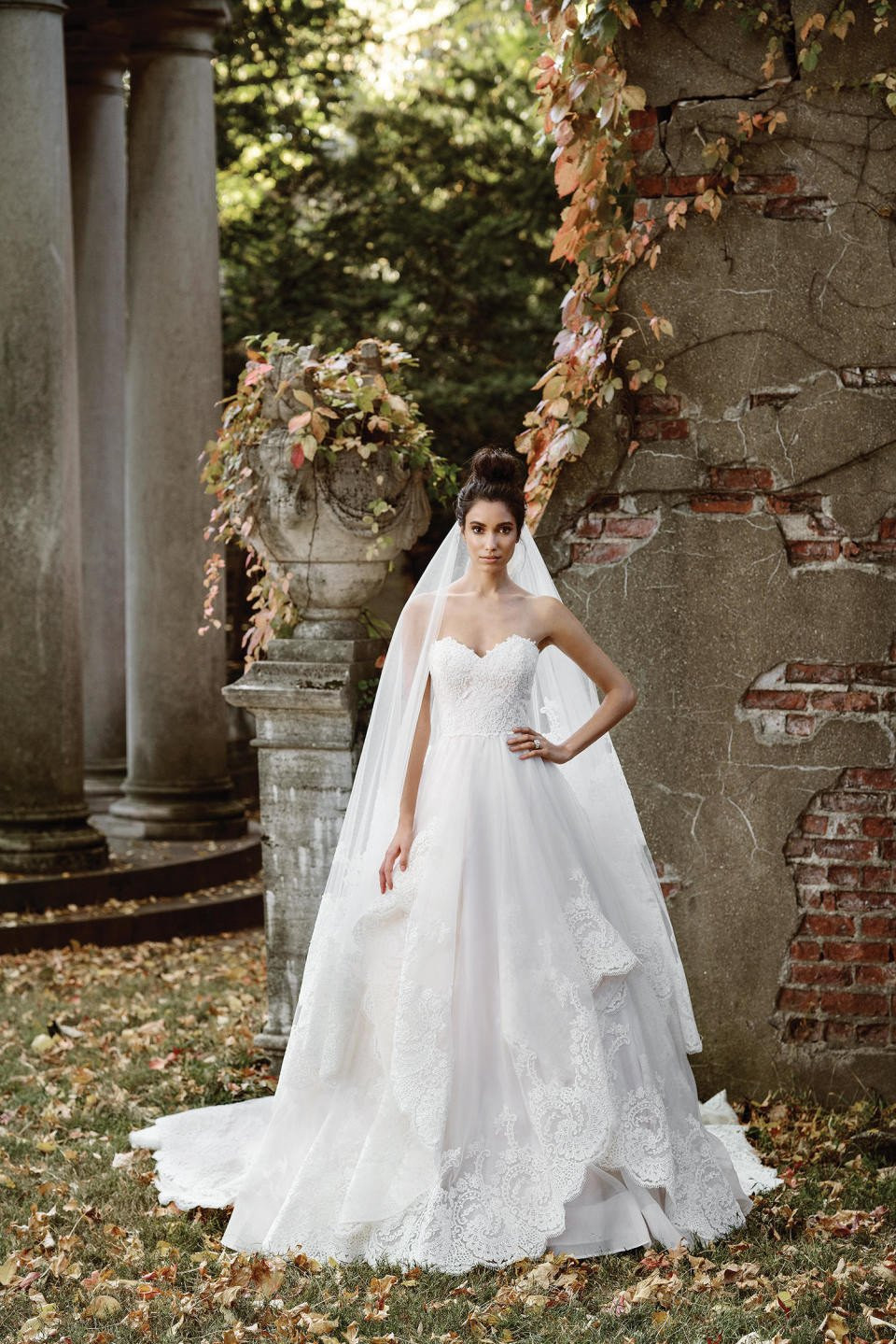 een bruid in een trouwjurk die voor een stenen zuil staat