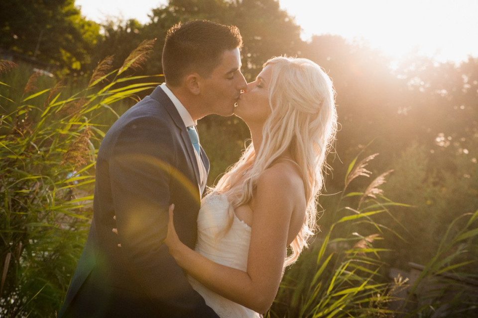 een bruid en bruidegom kussen voor de zon