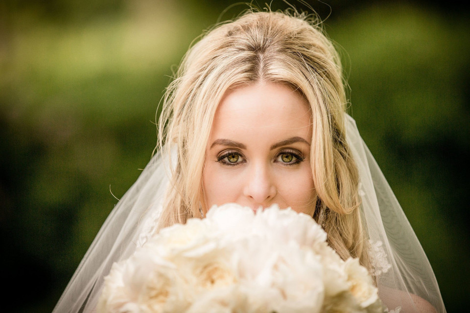 een mooie blonde bruid met een boeket witte bloemen