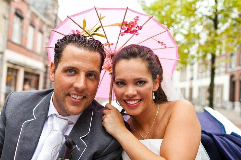 een bruid en bruidegom poseren voor een foto onder een paraplu