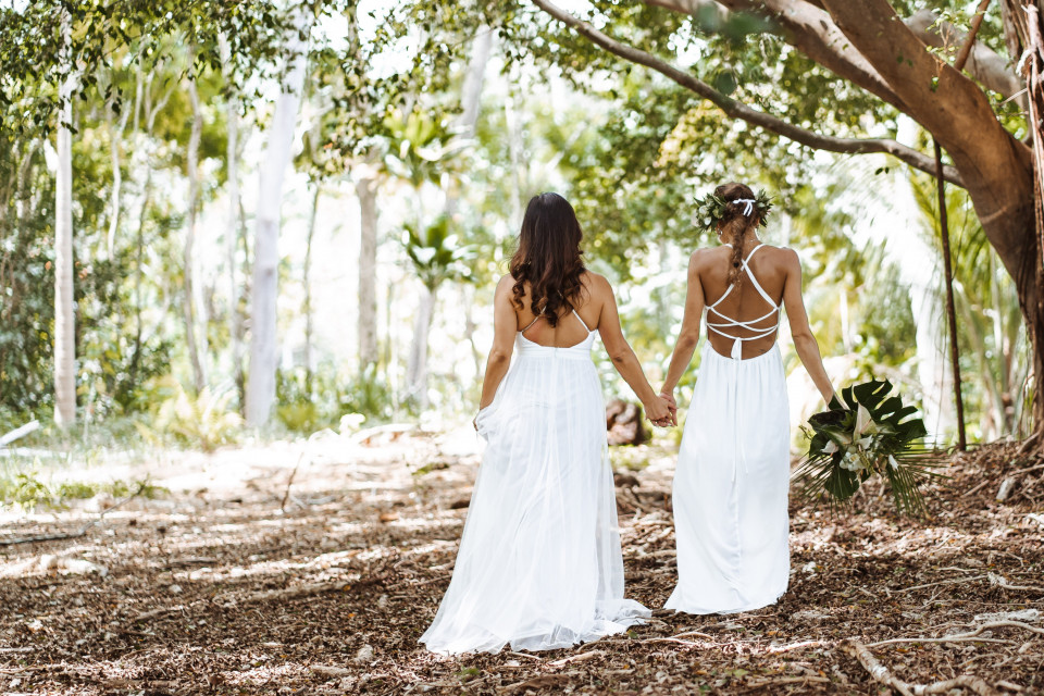 twee bruiden lopen hand in hand door het bos