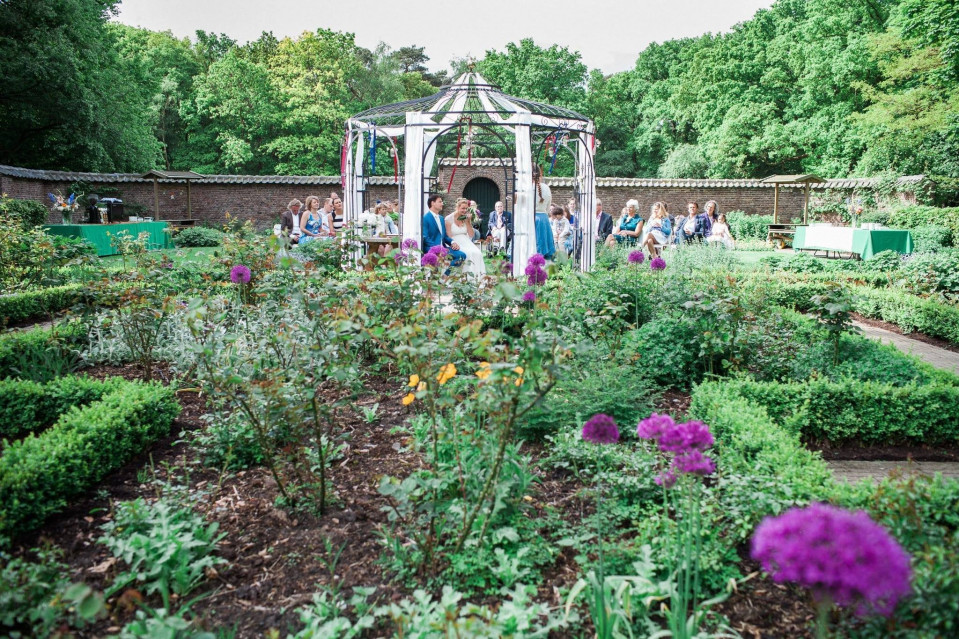 een bruiloftsceremonie in een tuin met paarse bloemen