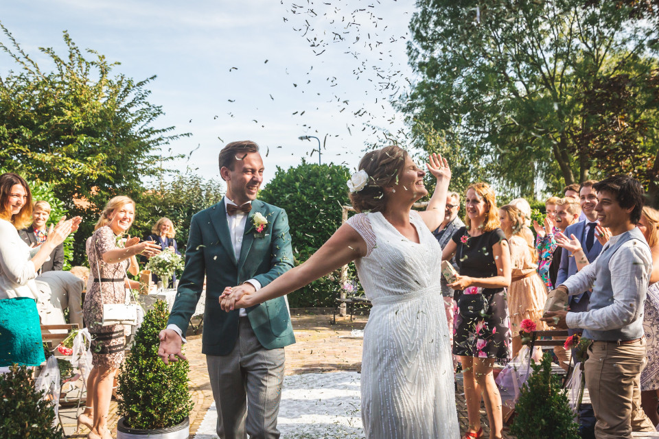een pasgetrouwd stel loopt het gangpad af met confetti