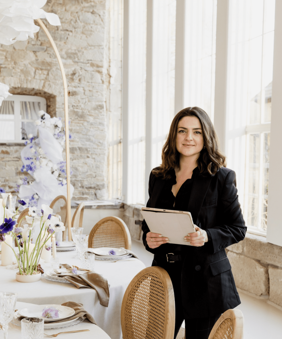 een vrouw die voor een tafel met stoelen staat