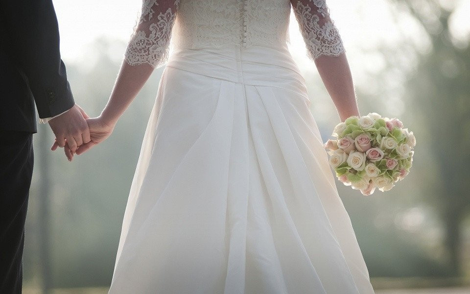 een bruid en bruidegom die elkaars handen vasthouden in het zonlicht