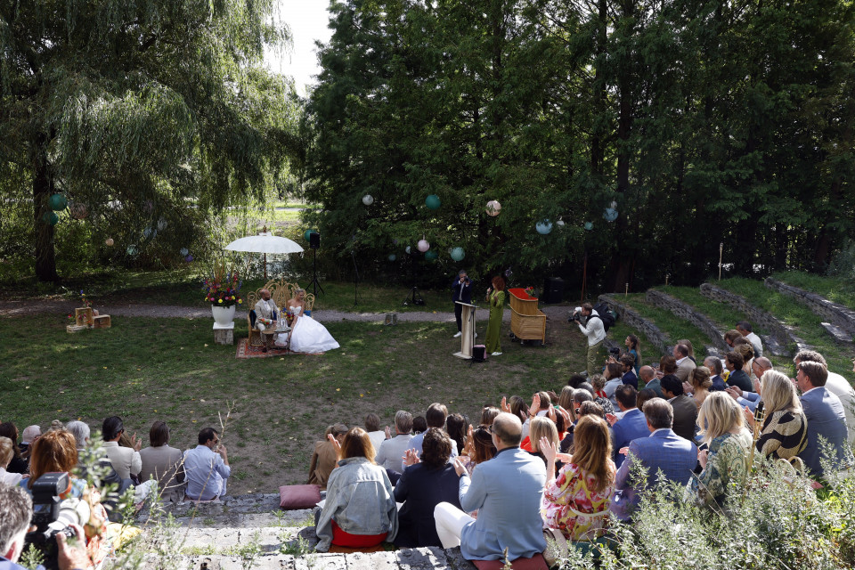 een bruiloftsceremonie in het park met mensen die op het gras zitten