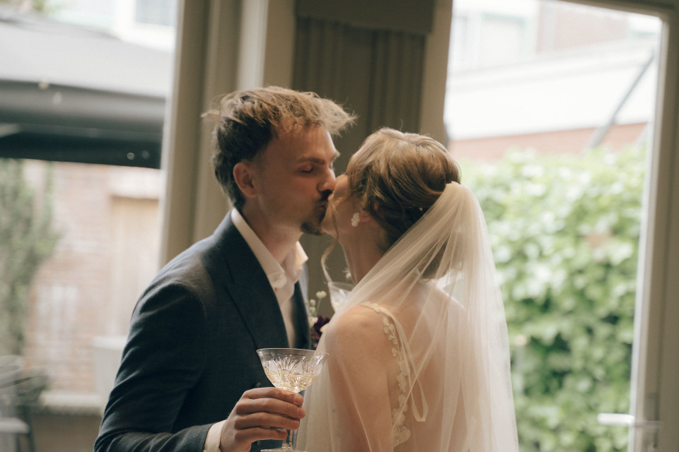 een bruid en een bruidegom die kussen voor een raam