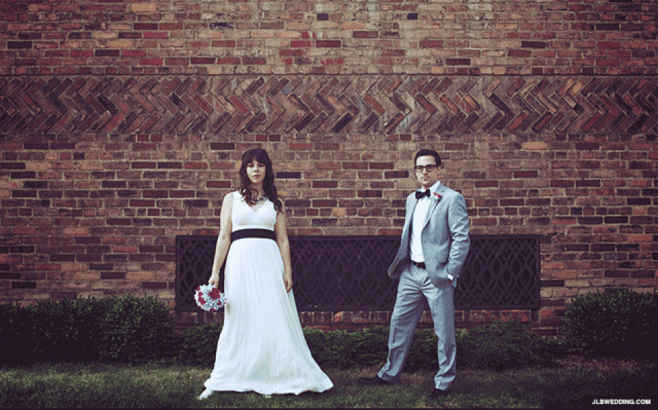 een bruid en bruidegom staan voor een bakstenen muur
