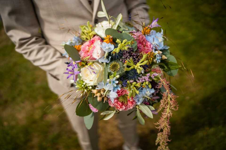 een man in een pak die een boeket bloemen vasthoudt