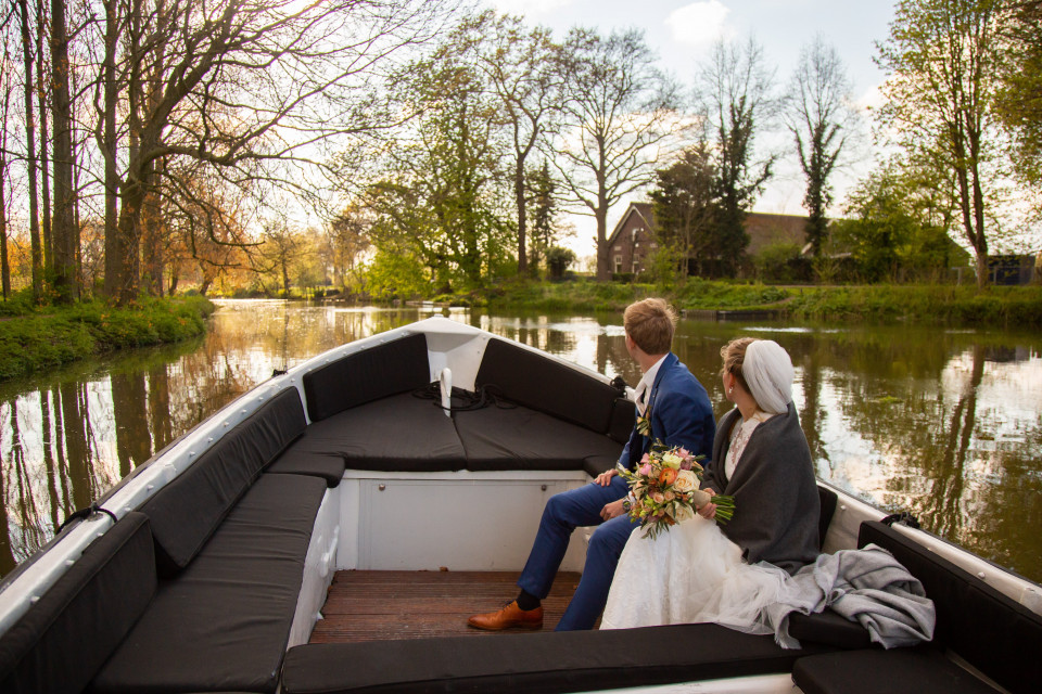 een bruid en bruidegom op een boot in het midden van een rivier