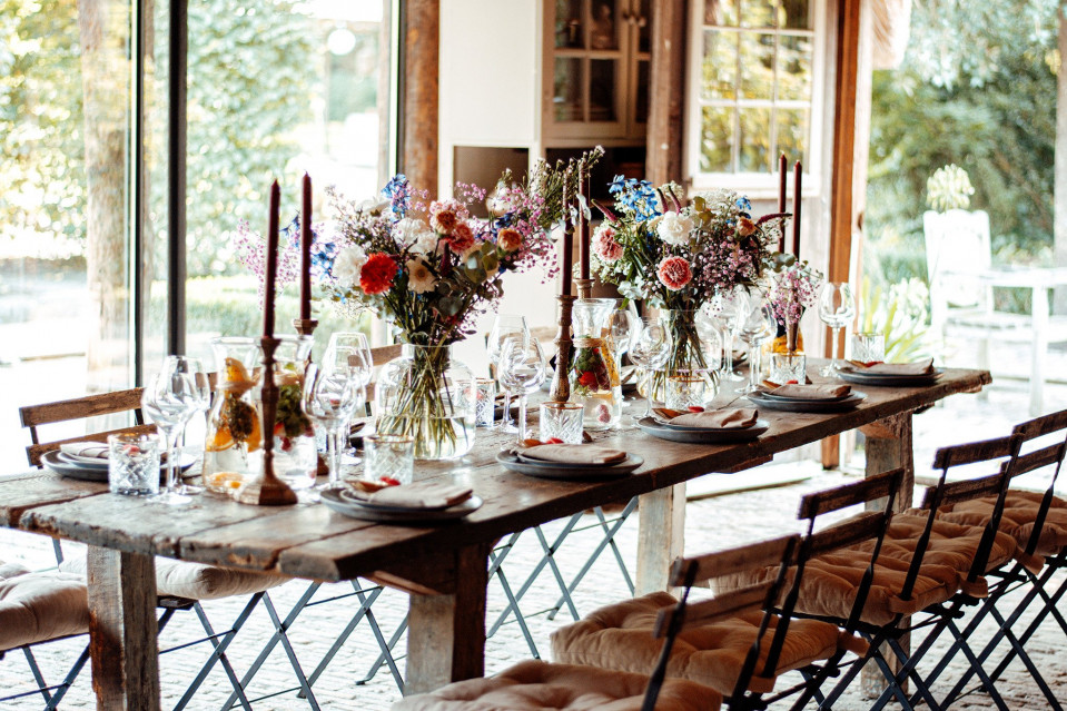 een rustieke tafel met stoelen en bloemen erop