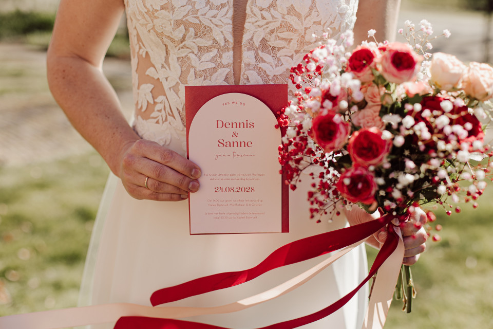 een vrouw in een trouwjurk die een boeket bloemen vasthoudt
