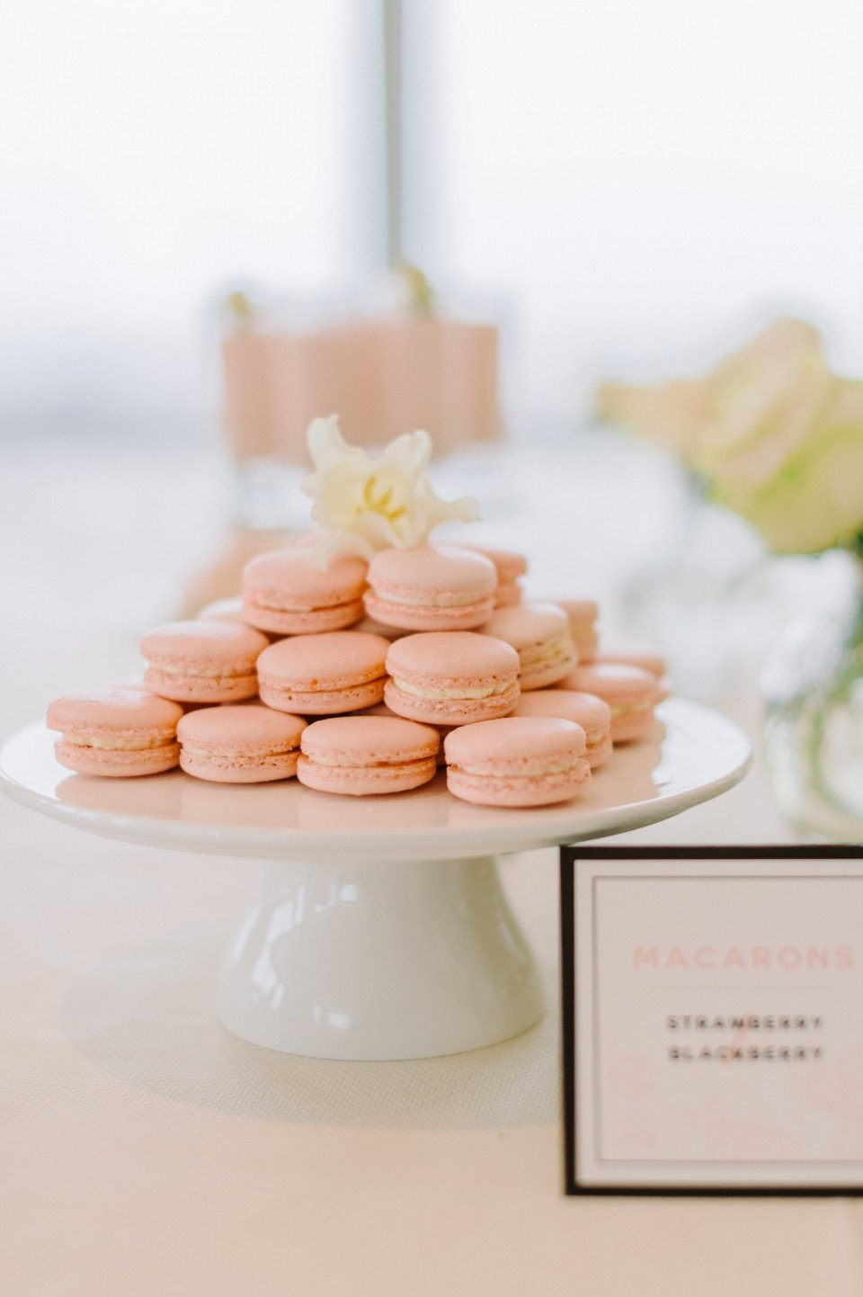 een witte cake met roze macarons erop