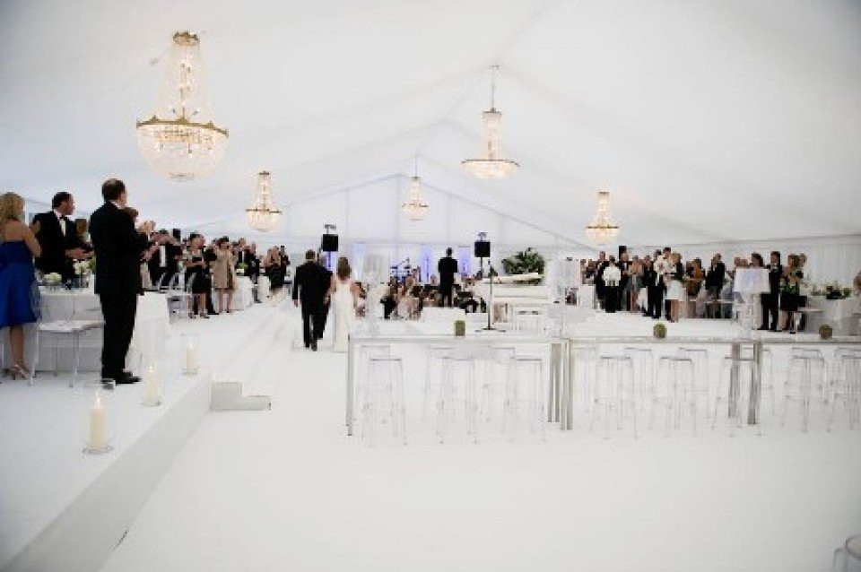 een bruiloftsreceptie in een witte tent met kroonluchters