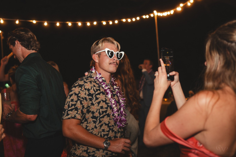 een man in een Hawaïaans shirt en zonnebril op een feest
