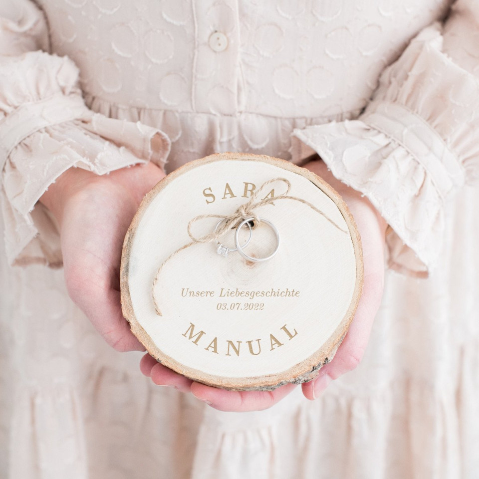 een vrouw die een houten plak met een ring erop vasthoudt