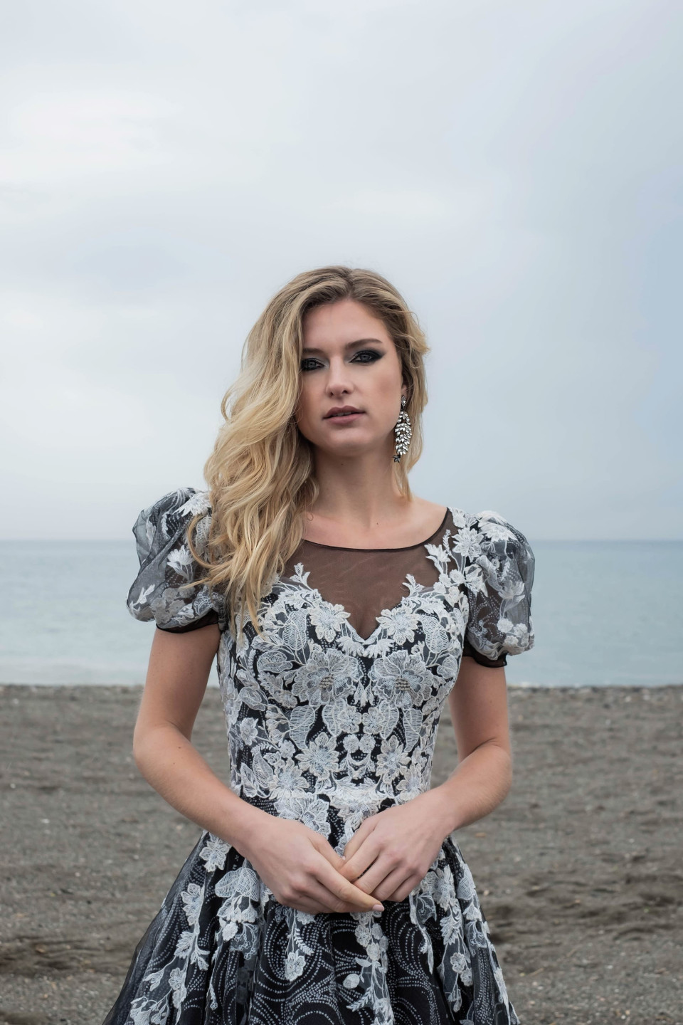 een vrouw in een zwart-witte jurk die op het strand staat