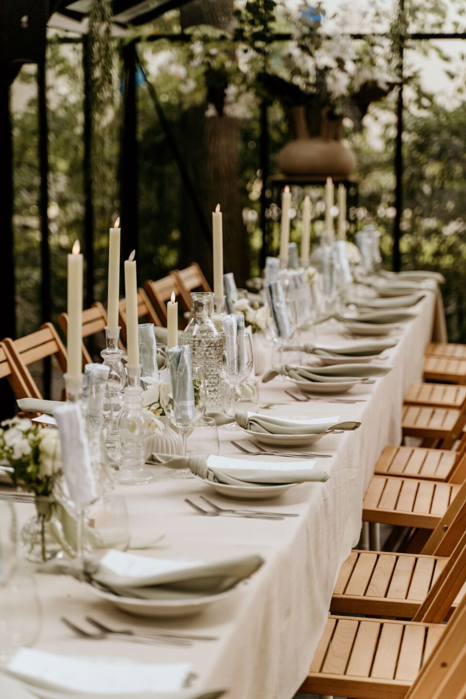 een lange tafel gedekt met witte borden en kaarsen