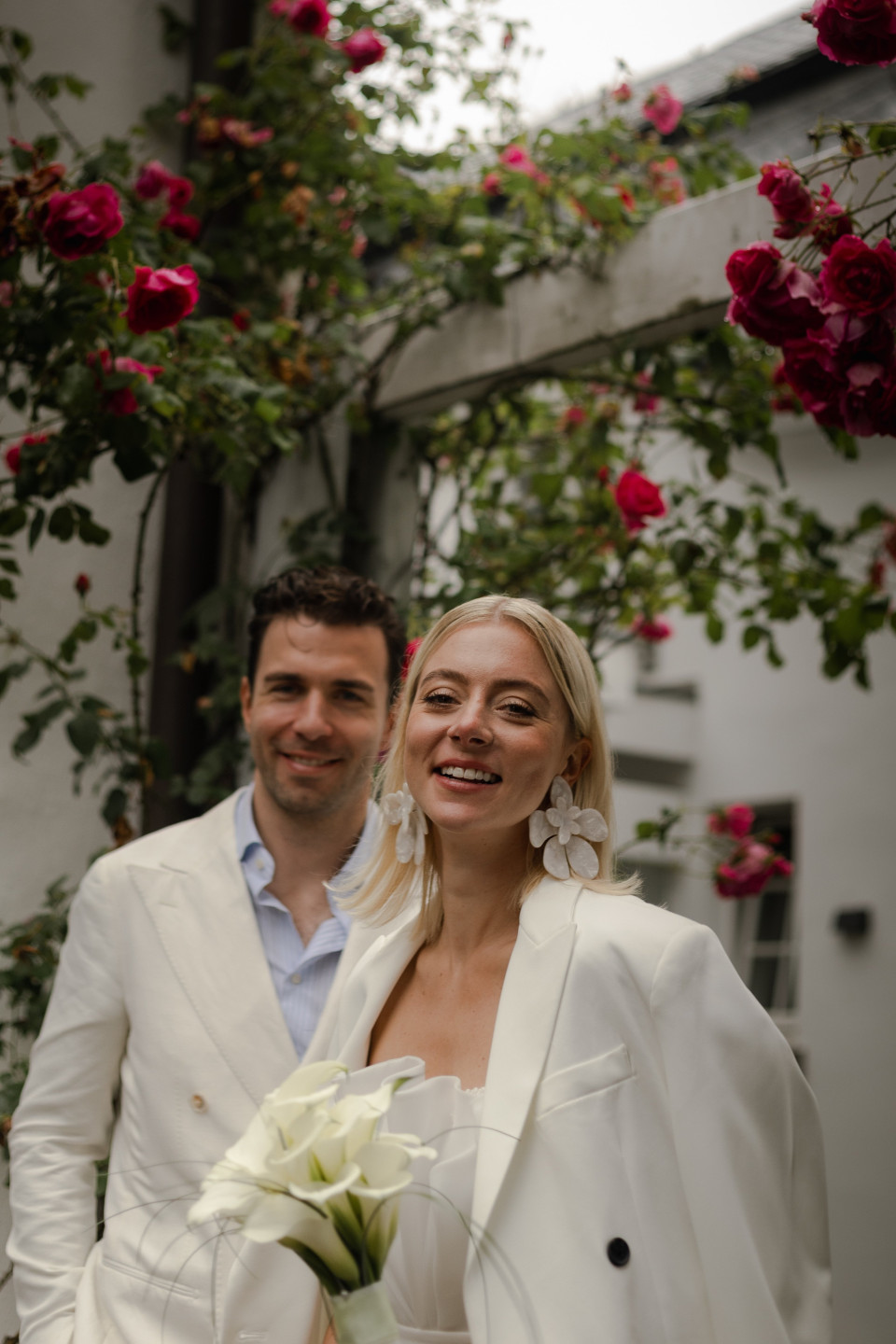 een man en vrouw in witte pakken staan voor rozen