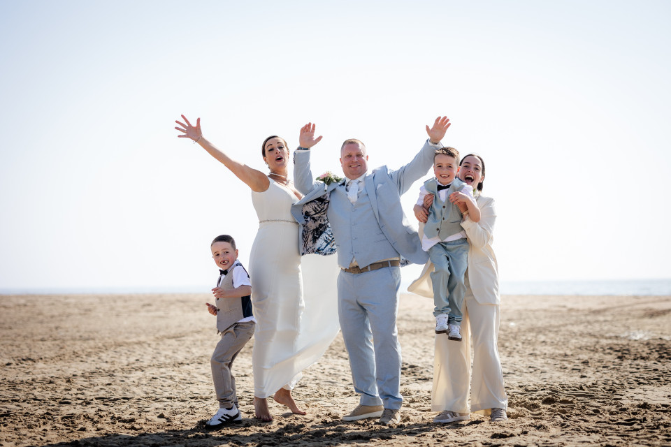 de bruid en bruidegom met hun kinderen op het strand
