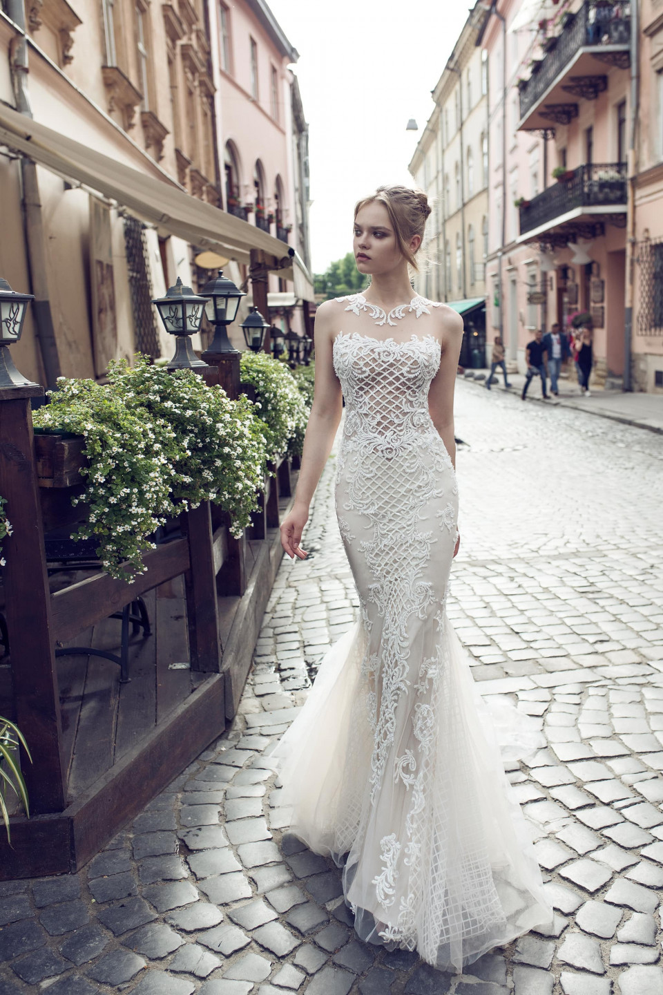 een mooie bruid in een trouwjurk loopt over een straat met keien