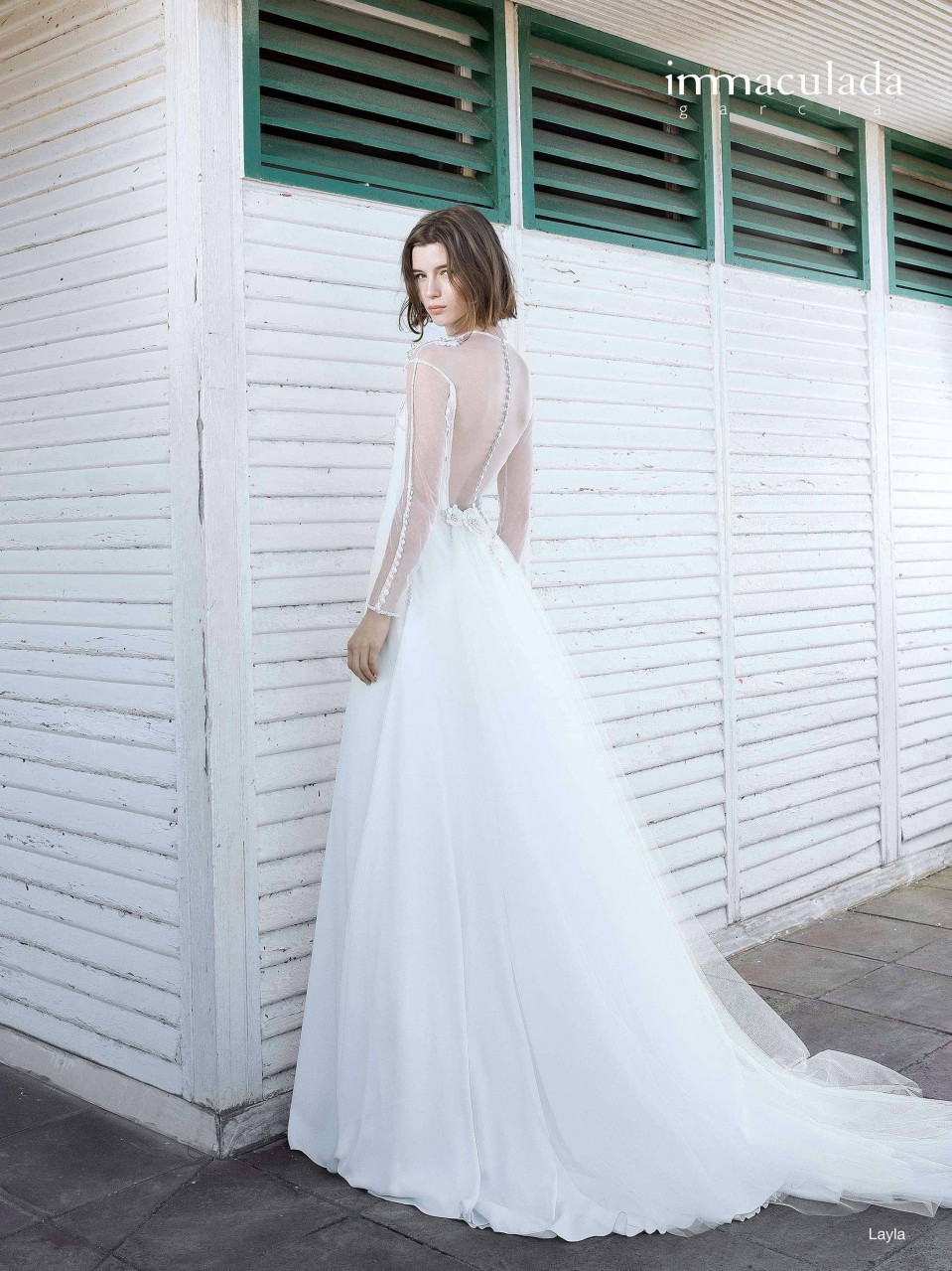 een vrouw in een trouwjurk die bij een muur staat