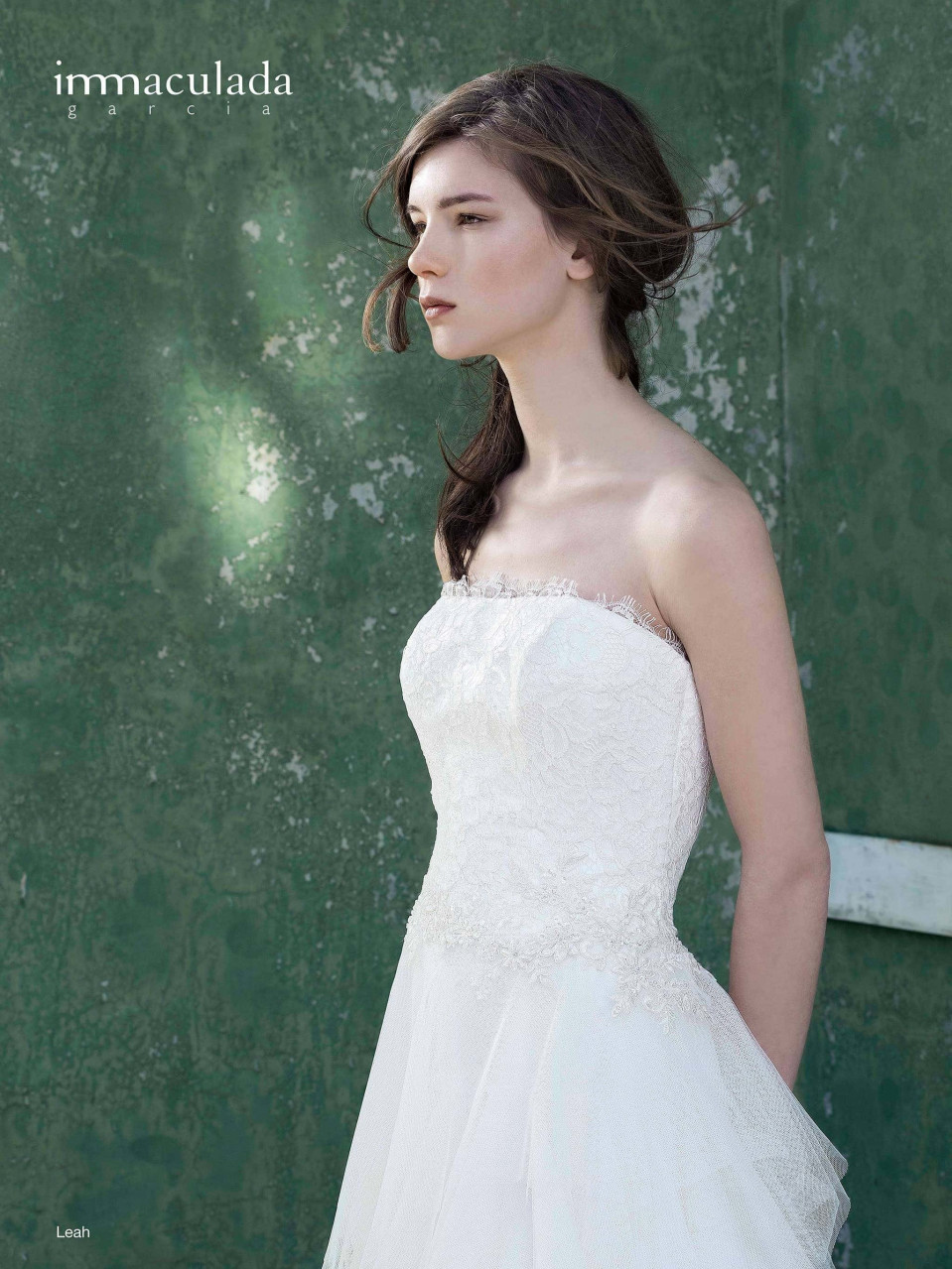 een vrouw in een trouwjurk die tegen een muur staat