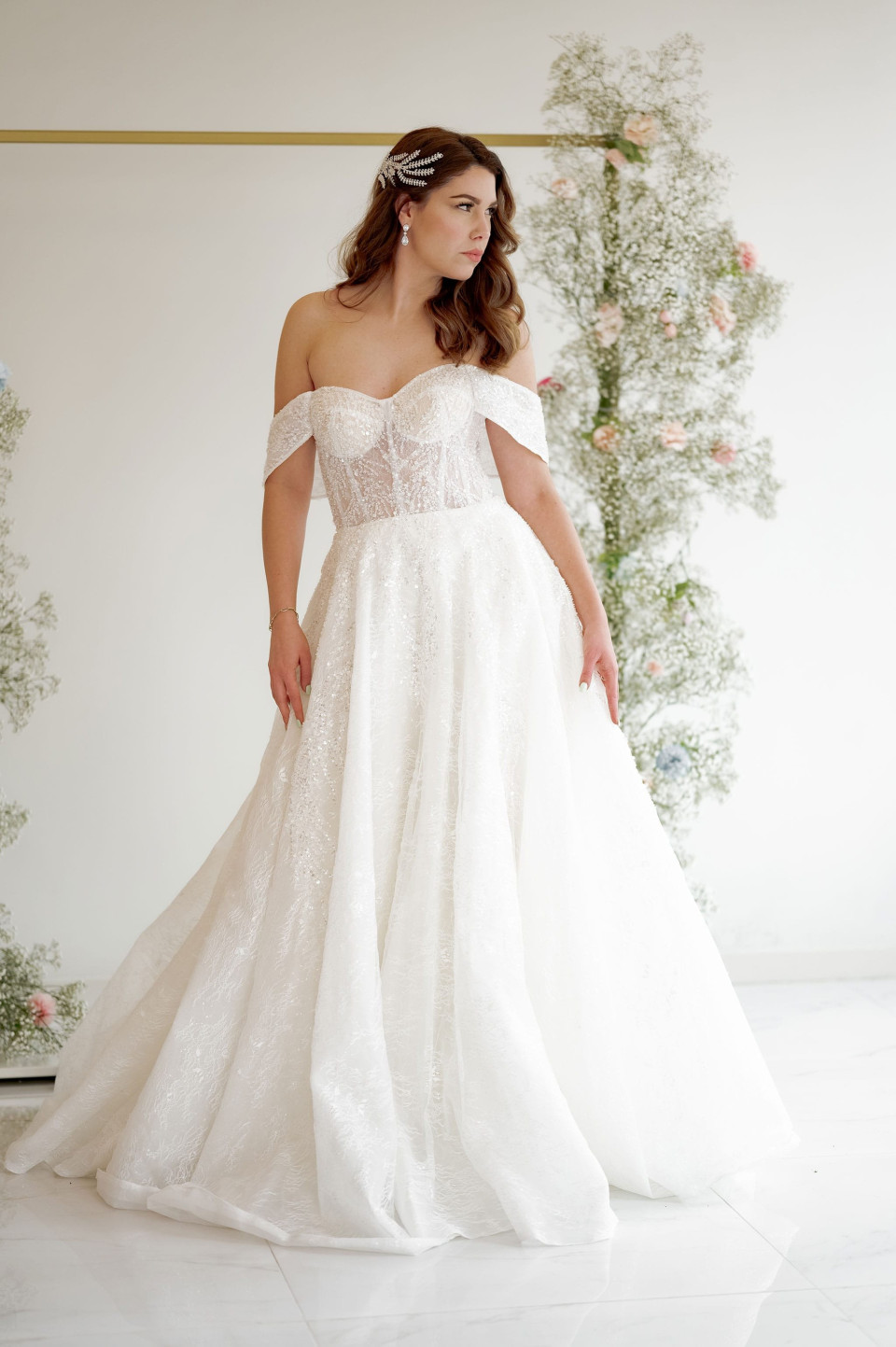 een vrouw in een trouwjurk staand voor een bloemstuk