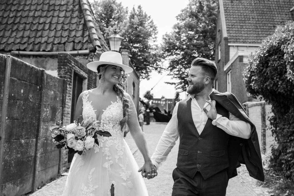 een bruid en bruidegom lopen door een smal steegje