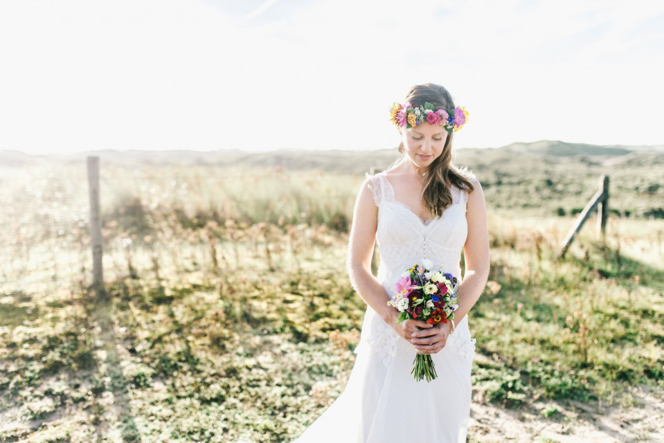 een bruid in een witte jurk die een boeket vasthoudt in het gras