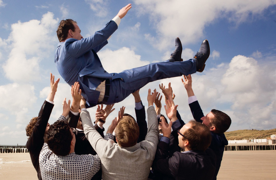 een man in pak wordt door een groep zakenmensen omhoog gegooid