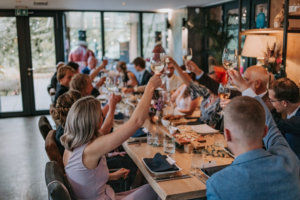 mensen in een restaurant die proosten met wijnglazen