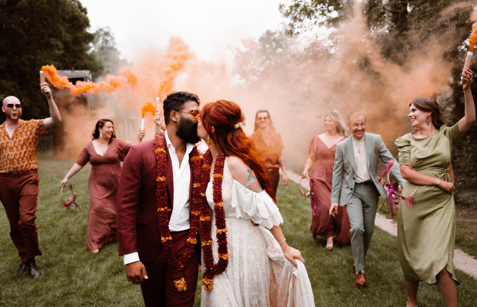 een bruid en bruidegom kussen met hun bruiloftsgasten op de achtergrond