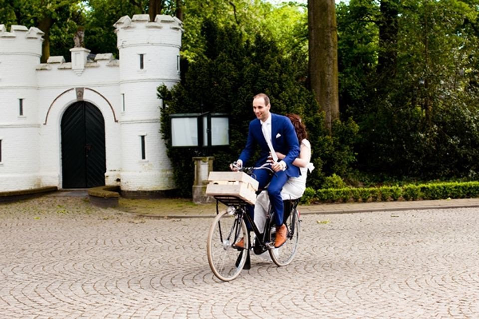 een bruid en bruidegom rijden op een fiets voor een kasteel