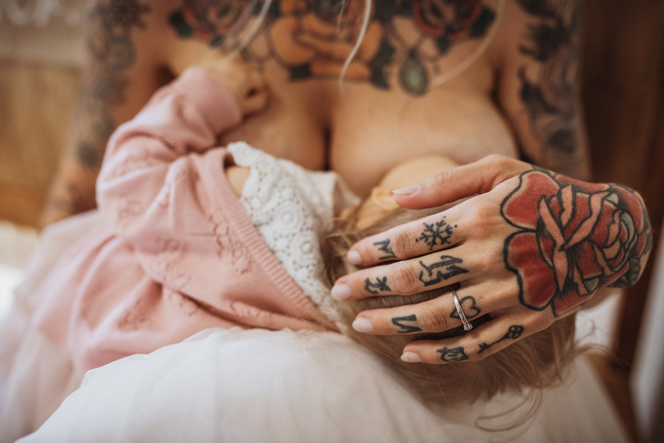 een vrouw met tatoeages die een baby vasthoudt