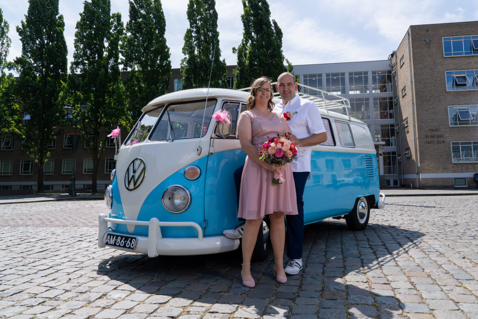 een man en een vrouw die naast een blauwe en witte vw-bus staan