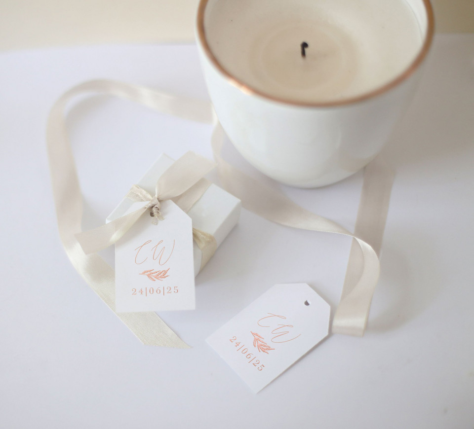 een witte kaars en een wit cadeaulabel liggen op een tafel