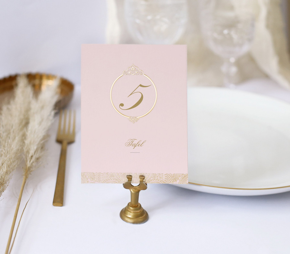 een tafelsetting met een roze kaart en gouden bord