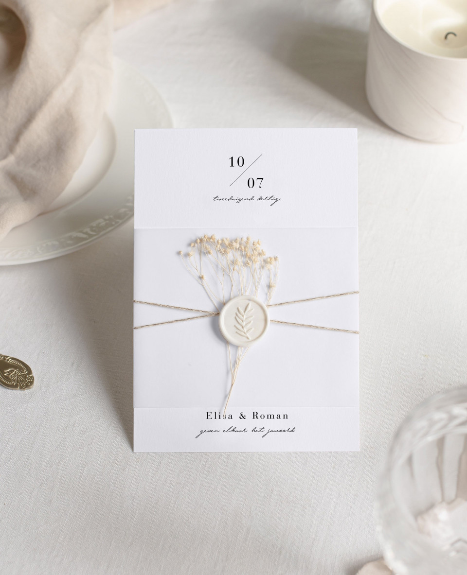 een trouwuitnodiging met een witte bloem erop