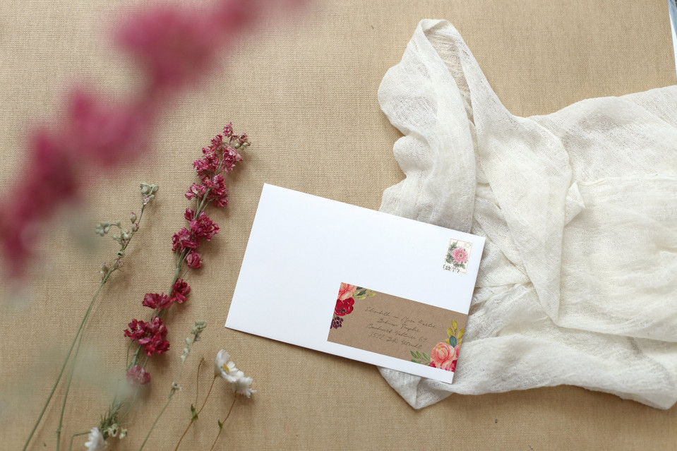 een witte envelop met een roze bloem erop