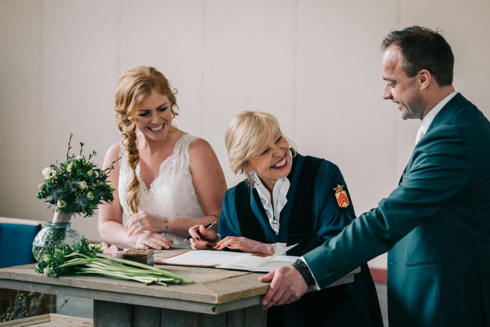 een bruid en bruidegom die hun huwelijksakte ondertekenen