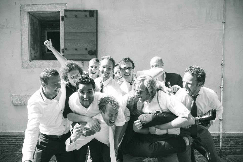 een groep mannen in witte overhemden en stropdassen die elkaar omhelzen