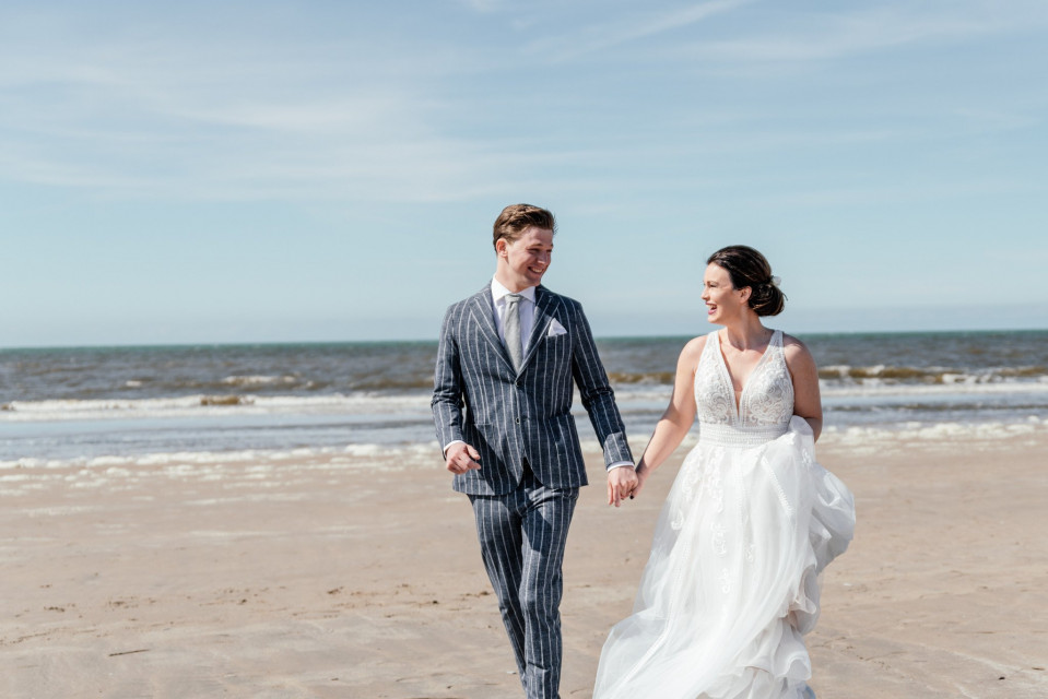 een bruid en bruidegom lopen langs het strand