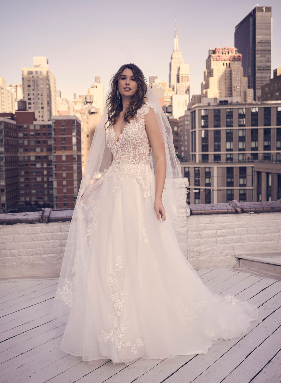 een bruid in een trouwjurk die op een dak staat voor de stad