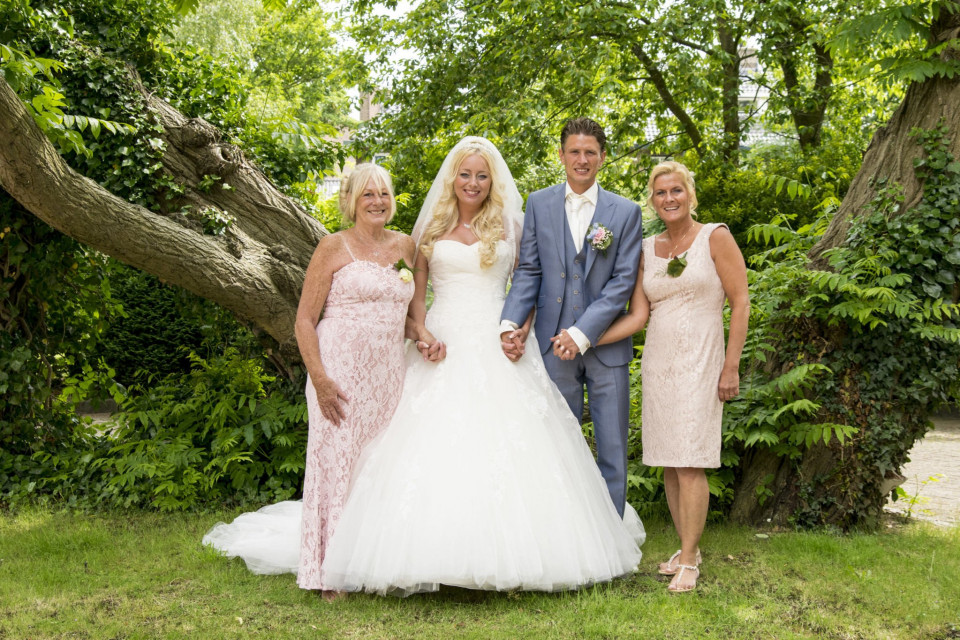 een bruid en bruidegom poseren met hun ouders