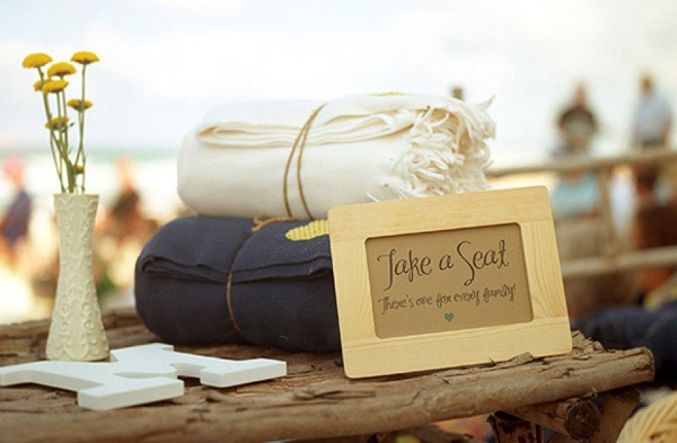 een houten tafel met handdoeken en een bord met de tekst 'laat een zegel achter'