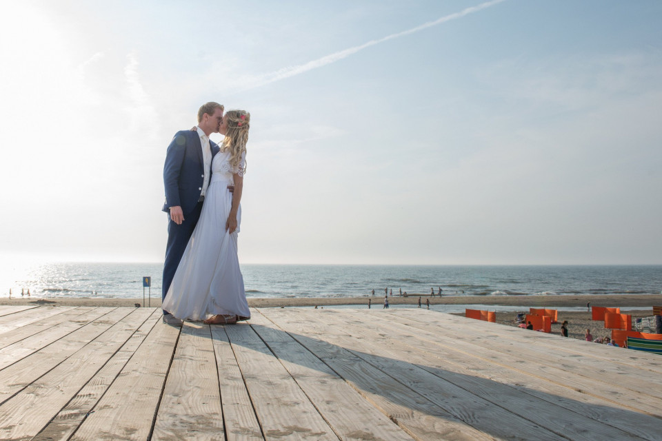 een bruid en bruidegom staan op een houten pier