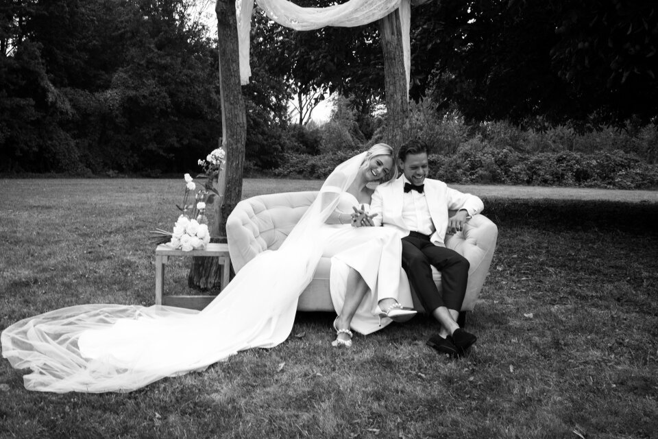 een zwart-wit foto van een bruid en bruidegom die op een bankje zitten