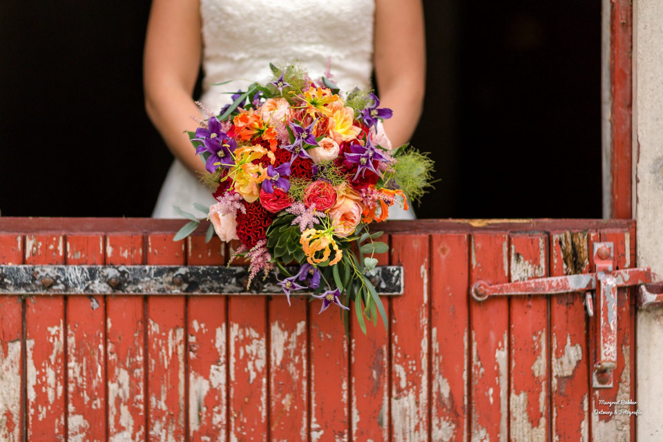 een bruid die een kleurrijk boeket vasthoudt voor een schuur